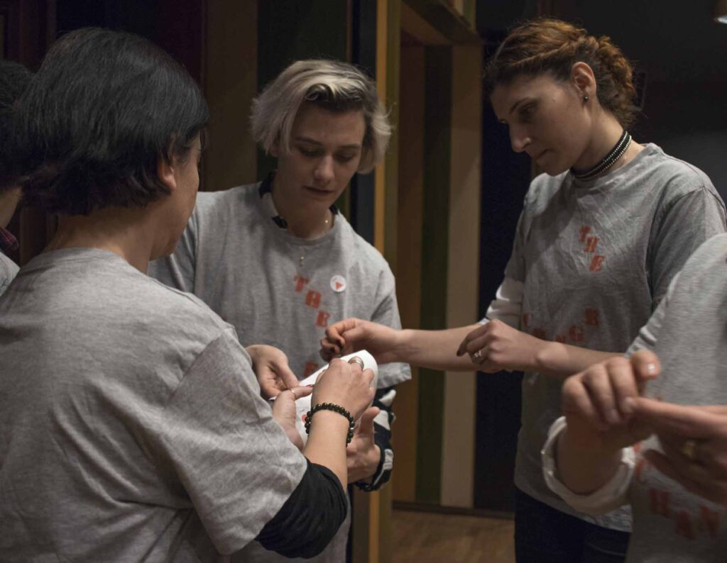 3 young people in grey t-shirts handing out stickers, The Exchange, Ankara, photo: Mert Oener