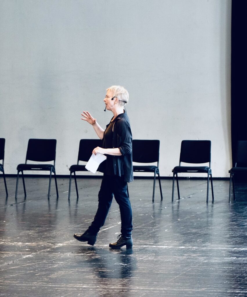 Image of author Dana Caspersen, walking and gesturing in a workshop.